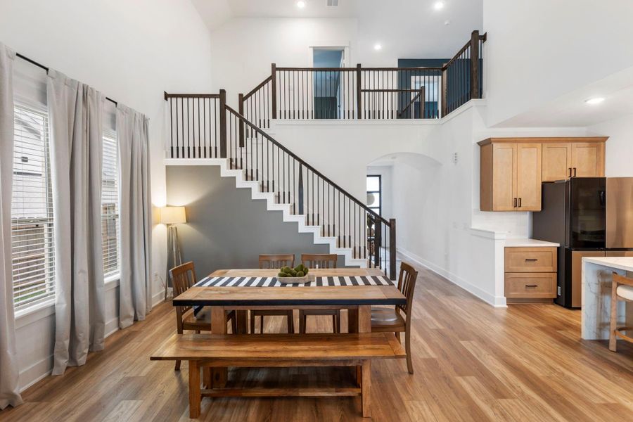 This bright, open-concept living space features high ceilings and a modern staircase leading to an upper level. The dining area includes space for a large dining table and is open to the kitchen and living room. This bright, open-concept living space features high ceilings and a modern staircase leading to an upper level. The dining area includes space for a large dining table and is open to the kitchen and living room.