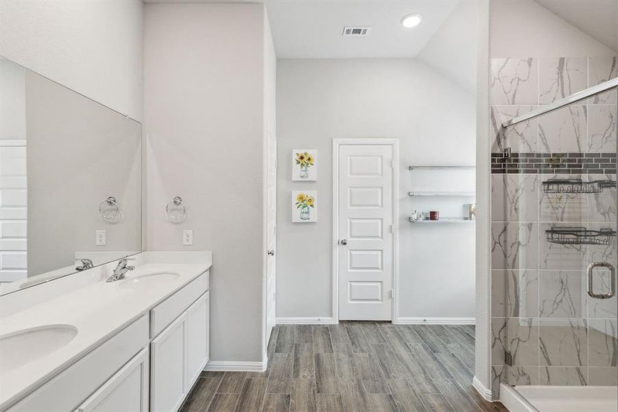 Primary bath featuring double vanity, large walk-in shower, and wood like tile floors Primary bath featuring double vanity, large walk-in shower, and wood like tile floors
