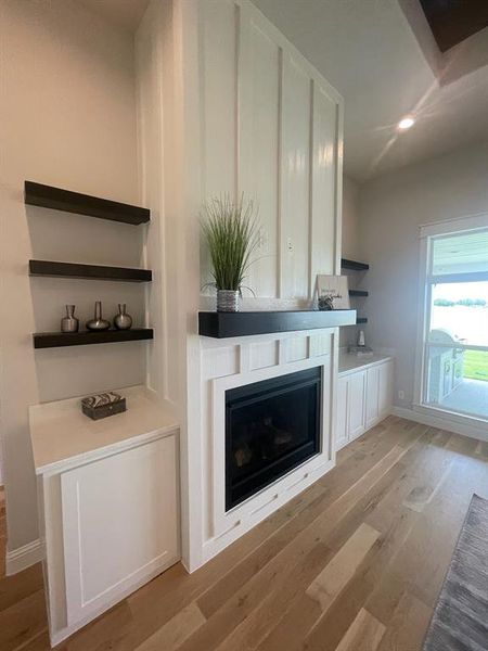 Detailed view of wood finished floors, a glass covered fireplace, recessed lighting, and baseboards Detailed view of wood finished floors, a glass covered fireplace, recessed lighting, and baseboards