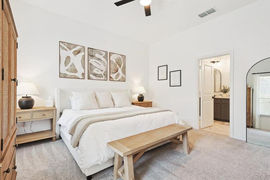 Carpeted bedroom with ensuite bath and ceiling fan