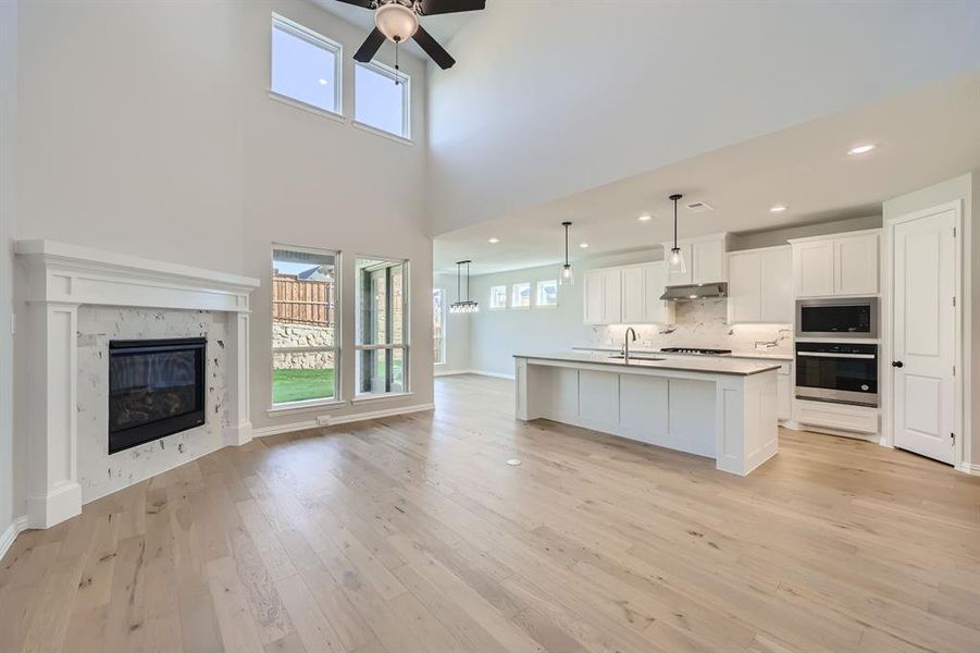 Kitchen featuring appliances with stainless steel finishes, white cabinets, plenty of natural light, and an island with sink