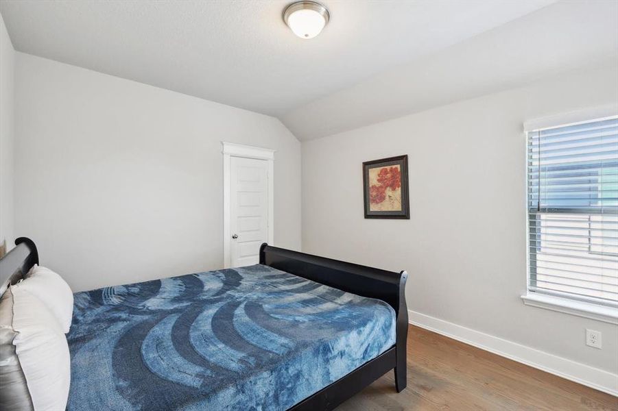 Bedroom with wood-type flooring and lofted ceiling