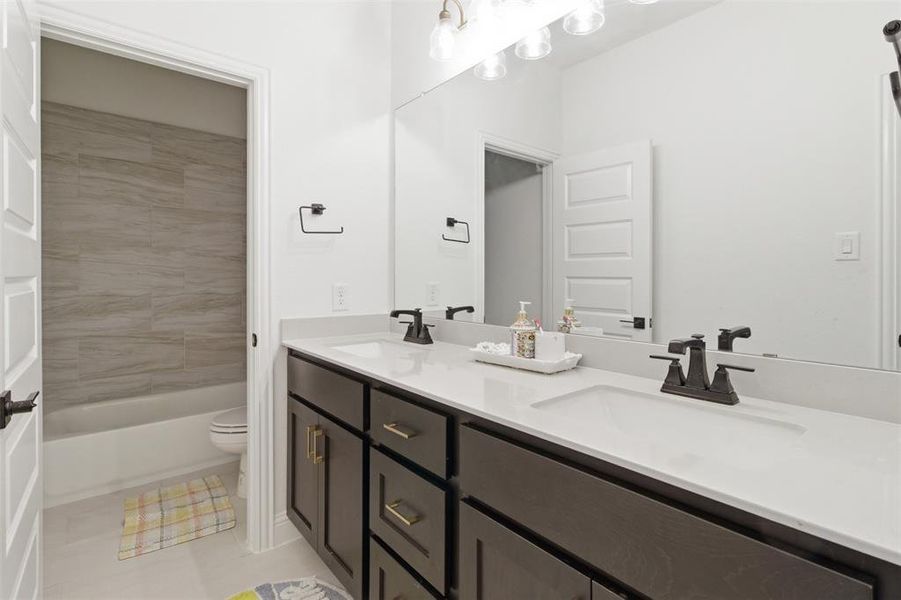 Dual vanity with white countertop and dark cabinetry, featuring matte black faucets and hardware