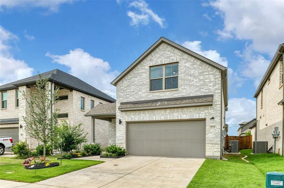 Traditional home featuring a front yard, brick siding, driveway, and an attached garage Traditional home featuring a front yard, brick siding, driveway, and an attached garage