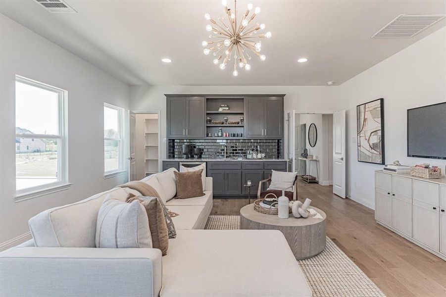 Living room with sink, an inviting chandelier, and light wood-type flooring