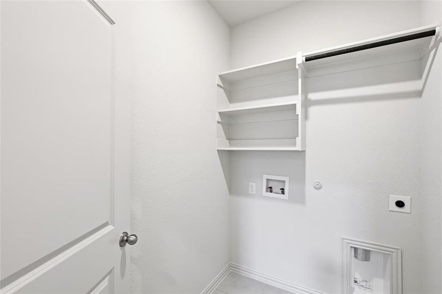 Utility room featuring built-in shelving, a garment rod, and plumbing hookups