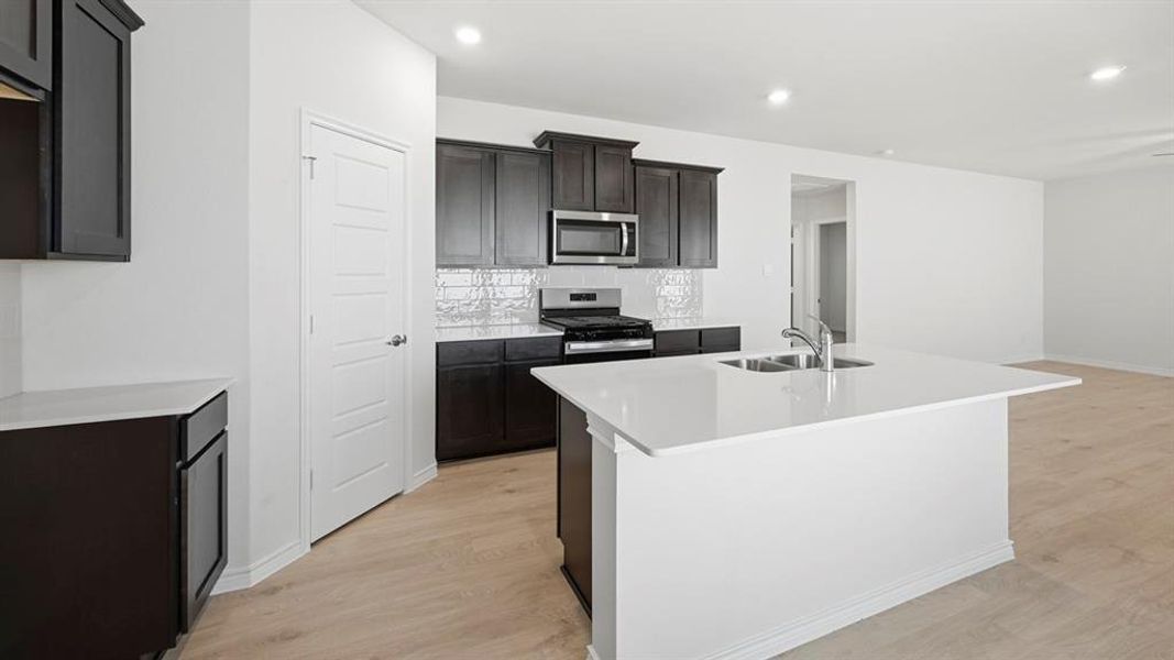Kitchen with light wood-style flooring, a kitchen island with sink, tasteful backsplash, stainless steel appliances, and recessed lighting