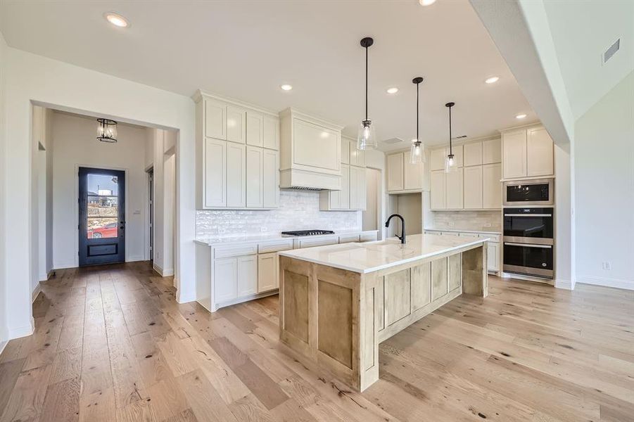 Kitchen featuring white cabinets, light hardwood / wood-style floors, and a spacious island