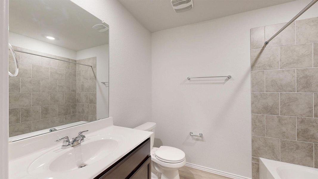 A well-appointed bath features a sleek vanity and tiled shower surround.