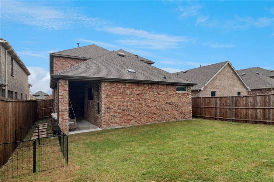 Rear view of property featuring a fenced backyard, a shingled roof, a patio area, and brick siding Rear view of property featuring a fenced backyard, a shingled roof, a patio area, and brick siding