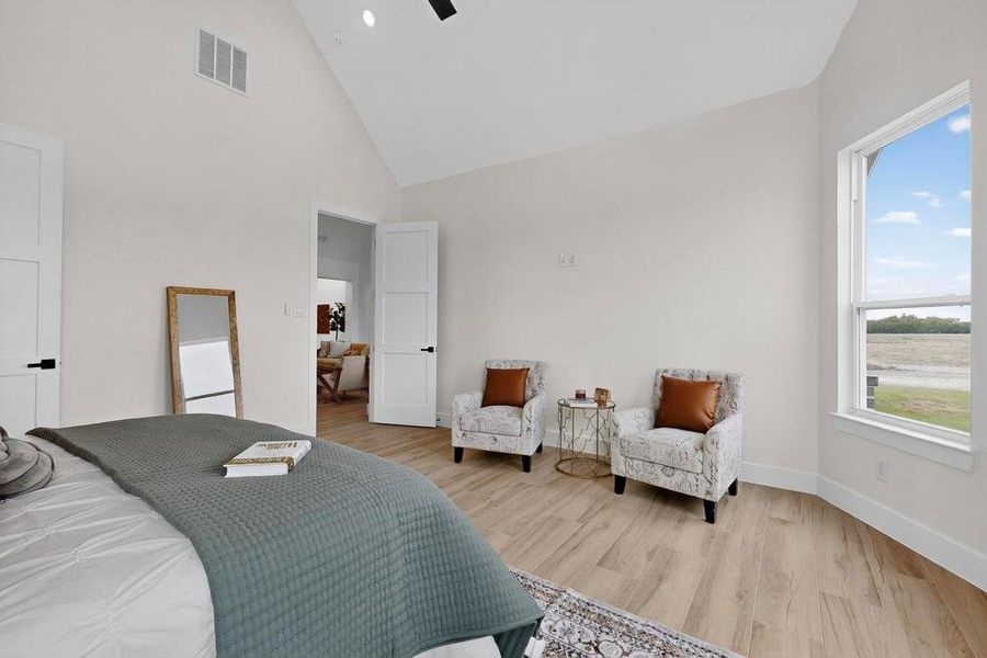 Bedroom featuring light wood-style flooring, high vaulted ceiling, a ceiling fan, and a water view Bedroom featuring light wood-style flooring, high vaulted ceiling, a ceiling fan, and a water view