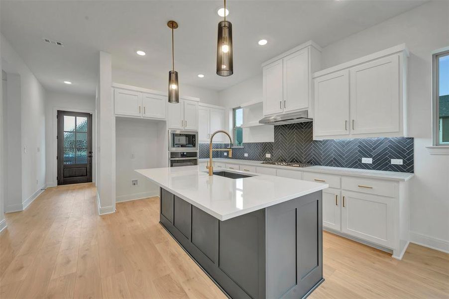 Contemporary kitchen featuring a large central island with a white countertop and dark base cabinetry