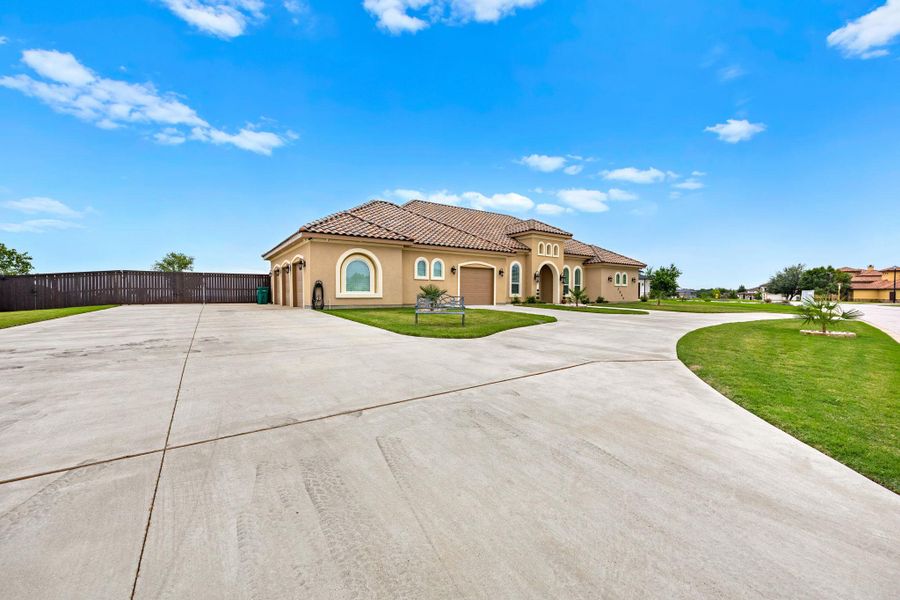 A spacious driveway welcomes you to this stucco residence featuring arched windows and a tile roof. A spacious driveway welcomes you to this stucco residence featuring arched windows and a tile roof.