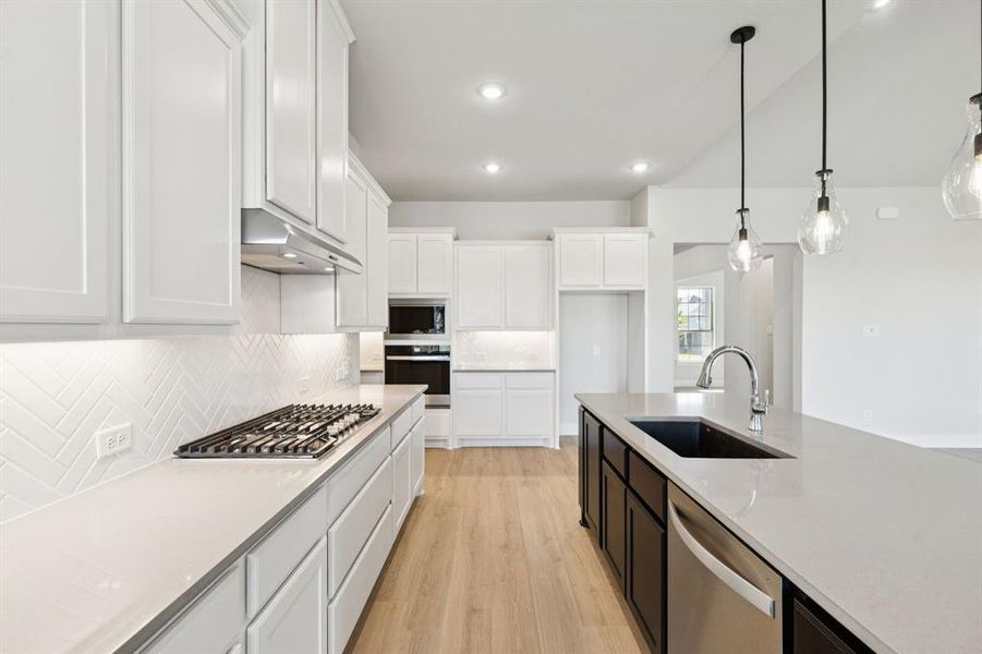 Kitchen with white cabinetry, light wood-style flooring, decorative light fixtures, backsplash, and recessed lighting