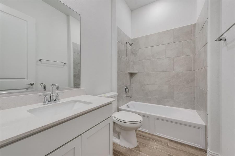 Full bathroom with tiled shower / bath, toilet, and vanity with extensive cabinet space