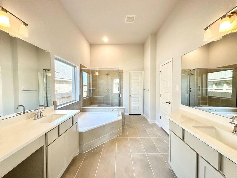 Full bathroom featuring two vanities, a bath, a stall shower, and tile patterned flooring Full bathroom featuring two vanities, a bath, a stall shower, and tile patterned flooring