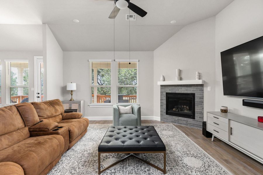 Living room with lofted ceiling, a fireplace, and ceiling fan