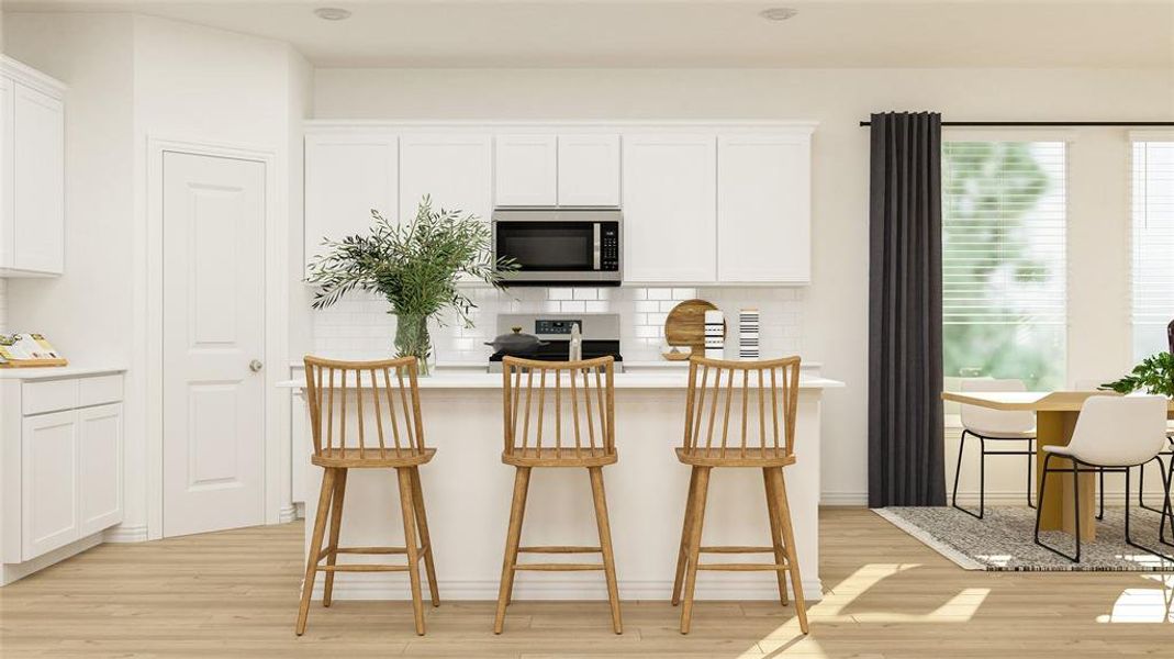 Kitchen featuring stainless steel appliances, white cabinets, decorative backsplash, light wood-type flooring, and a kitchen breakfast bar