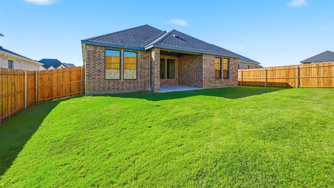 Back of house with a fenced backyard, a patio, roof with shingles, and brick siding