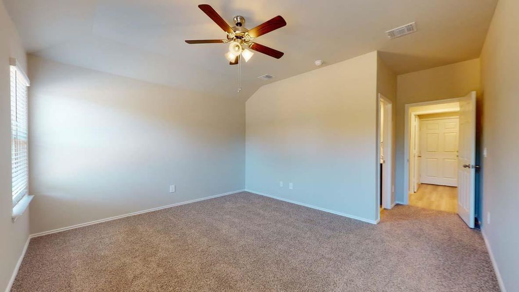 Carpeted room featuring a window with blinds, ceiling fan with integrated lighting, and a door leading to a separate area with wood-finish flooring