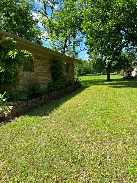 Brick exterior with a stone retaining wall, mature trees, and a spacious lawn Brick exterior with a stone retaining wall, mature trees, and a spacious lawn
