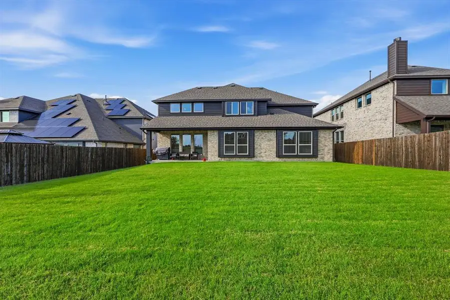 Expansive backyard featuring a manicured lawn, a covered patio, and a privacy fence