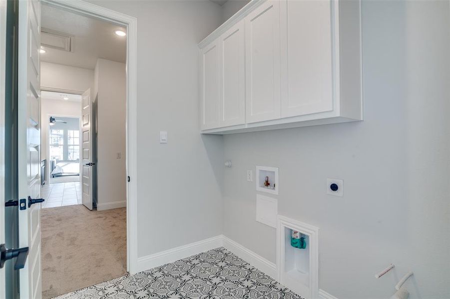 Washroom with cabinets, electric dryer hookup, gas dryer hookup, hookup for a washing machine, and light tile patterned flooring