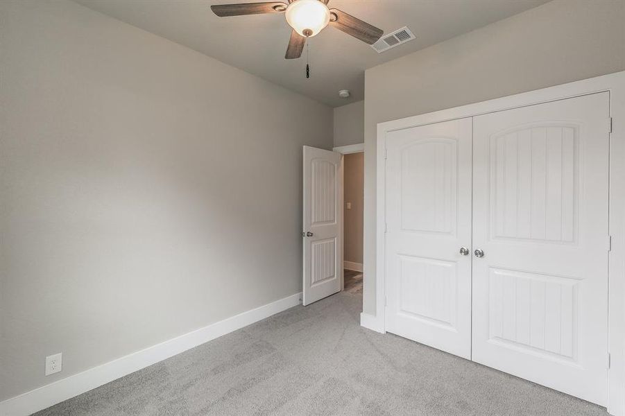 Unfurnished bedroom with light colored carpet, a closet, and ceiling fan