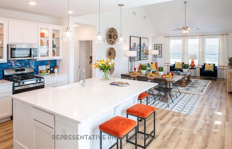Kitchen featuring a kitchen bar, white cabinets, glass insert cabinets, light wood finished floors, and lofted ceiling