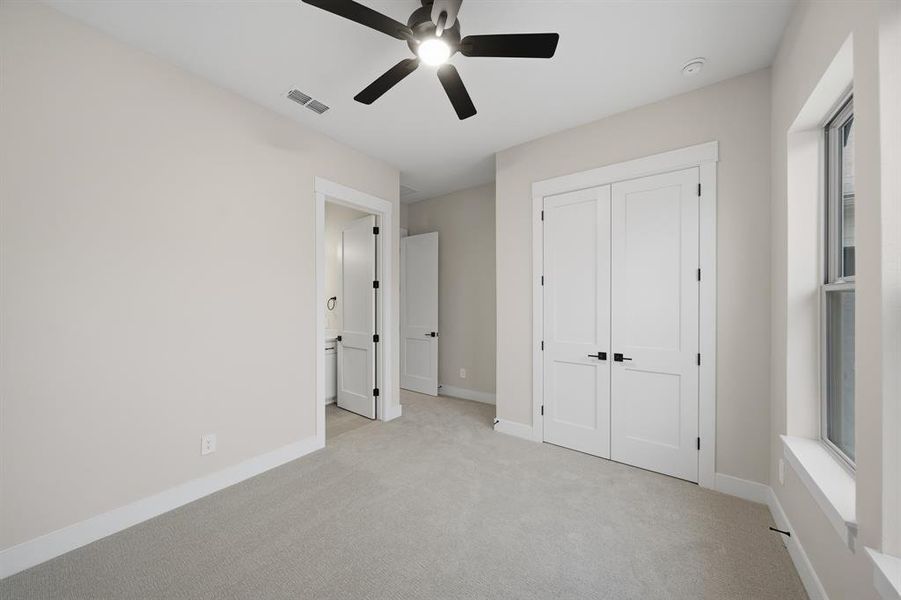 Unfurnished bedroom with carpet, a ceiling fan, a closet, and connected bathroom