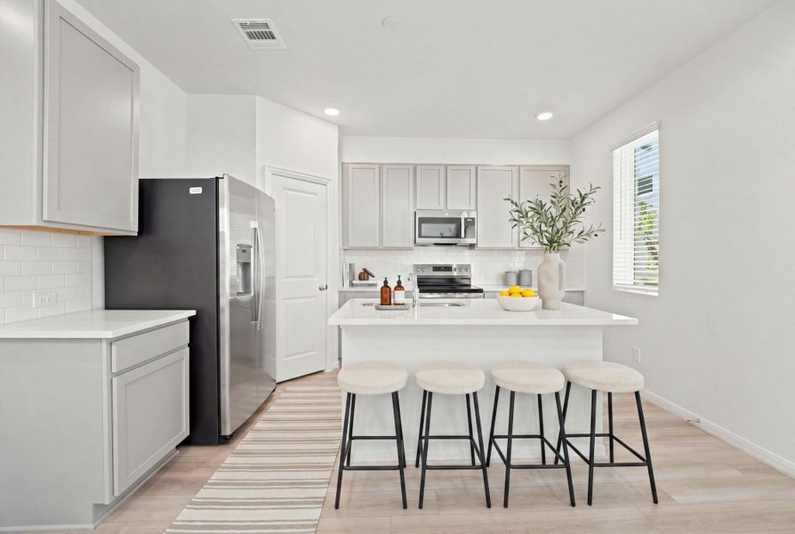 Clean lines and a central island with stone countertops define this modern cooking space.