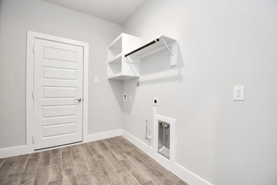 A perfect blend of functionality and comfort. Capture the essence of easy living with a first-floor laundry room, thoughtfully equipped with shelving for effortless organization. Both electric and gas connections available. Sample photo of completed home with similar floor plan. Actual colors and selections may vary.