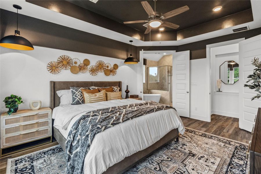 Bedroom with wood finished floors, connected bathroom, and a raised ceiling