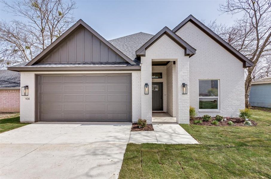 View of front of property featuring brick siding, a shingled roof, concrete driveway, board and batten siding, and a garage