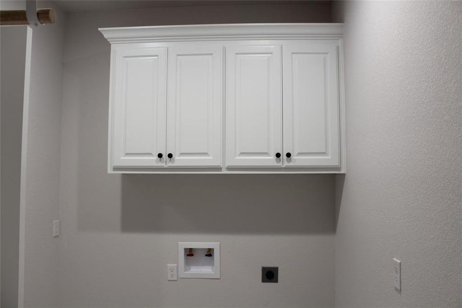 Washroom featuring electric dryer hookup, cabinet space, and hookup for a washing machine Washroom featuring electric dryer hookup, cabinet space, and hookup for a washing machine