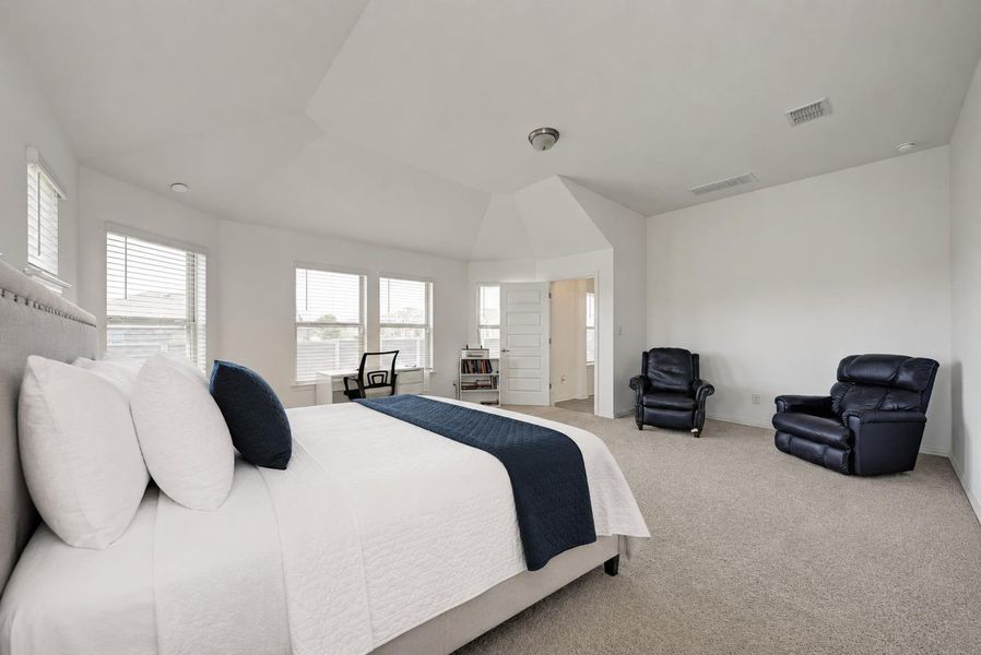 An airy bedroom with vaulted ceilings offers a dedicated workspace and abundant natural light.