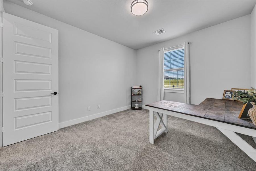 Room featuring carpet flooring, crisp white walls, a multi-paneled door with black hardware, and a window with blinds providing natural illumination
