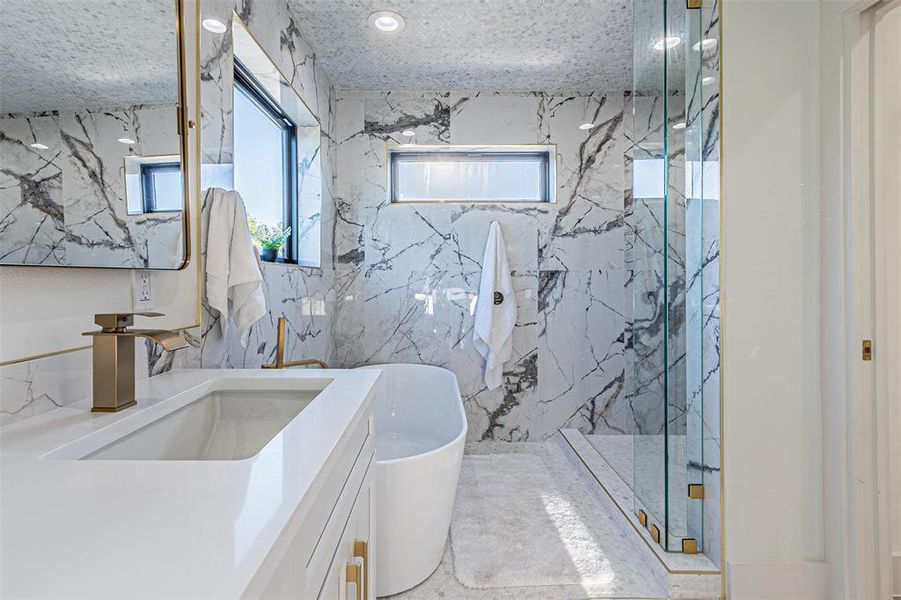 Full bathroom featuring stone wall, a marble finish shower, plenty of natural light, and vanity