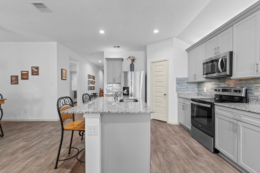Extended kitchen view highlights the island’s breakfast bar seating, upgraded shaker cabinetry, and thoughtful layout that connects easily to the dining area and family area and beyond. Looks like a model home, but with more upgrades. Extended kitchen view highlights the island’s breakfast bar seating, upgraded shaker cabinetry, and thoughtful layout that connects easily to the dining area and family area and beyond. Looks like a model home, but with more upgrades.