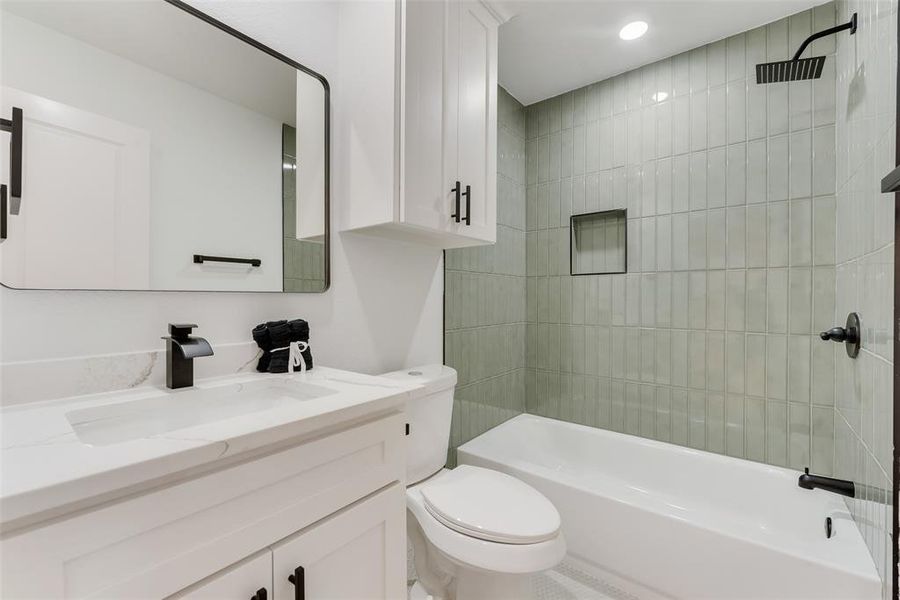 Full bathroom featuring vanity, tiled shower / bath combo, and toilet