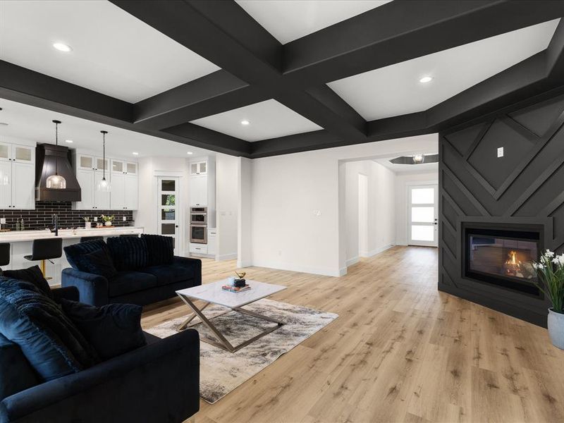 Spacious living area featuring a modern fireplace with a geometric surround, wood-finish flooring, and a coffered ceiling with recessed lighting