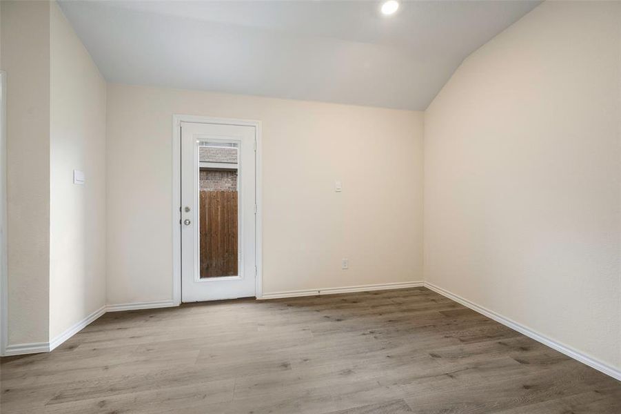Empty room featuring vaulted ceiling and wood finished floors
