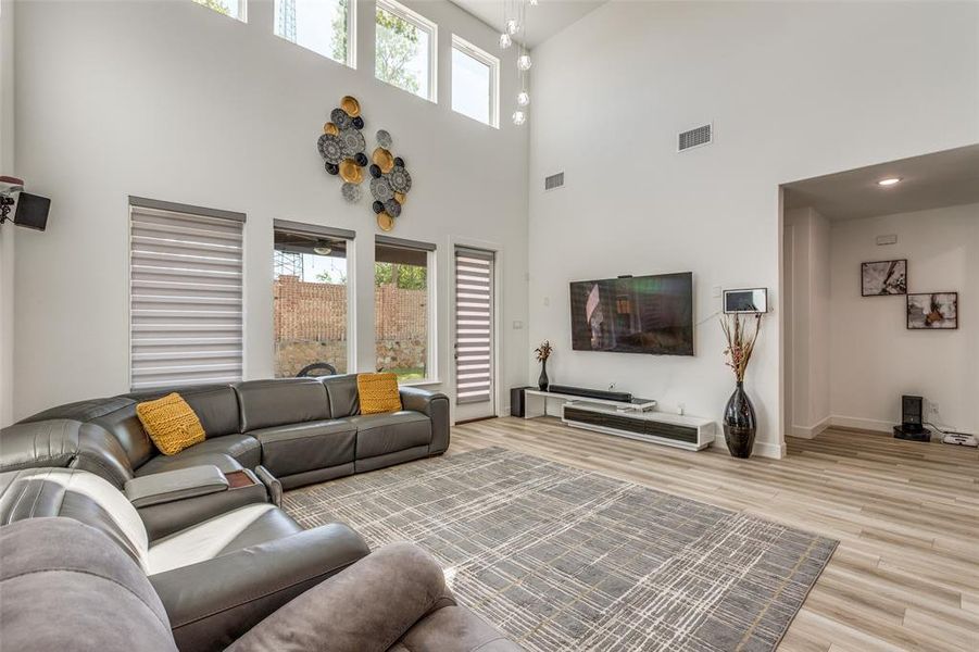 Flooded with natural light, the expansive two-story living room showcases soaring ceilings and warm light wood luxury plank flooring—an inviting space that feels both grand and welcoming! Flooded with natural light, the expansive two-story living room showcases soaring ceilings and warm light wood luxury plank flooring—an inviting space that feels both grand and welcoming!