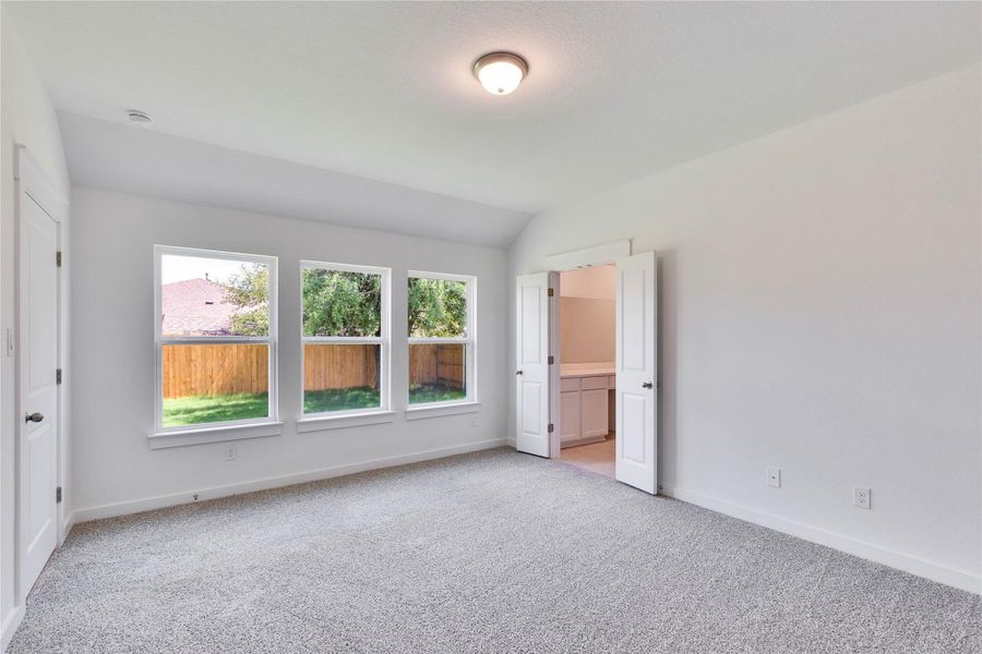 Unfurnished bedroom with light carpet, lofted ceiling, and ensuite bath Unfurnished bedroom with light carpet, lofted ceiling, and ensuite bath