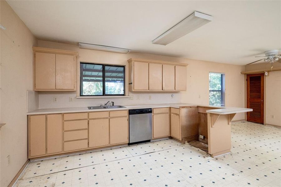 Kitchen featuring a wealth of natural light, kitchen peninsula, stainless steel dishwasher, and sink