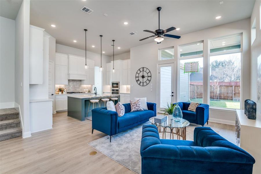 Living room with ceiling fan, light wood-type flooring, and sink