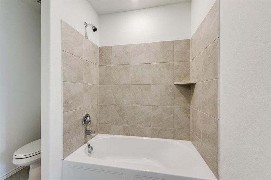 Bathroom featuring toilet and tiled shower / bath combo