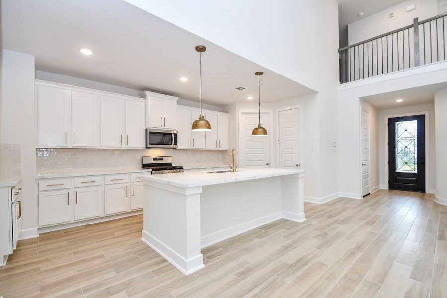 A pristine kitchen featuring dual islands, pendant lighting, and ample counter space.