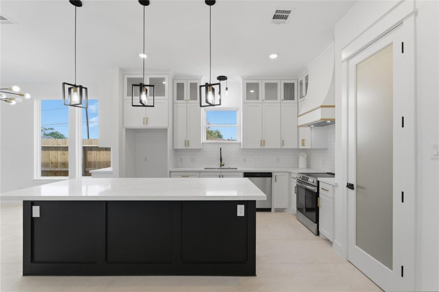 A bold black island adds the perfect pop and plenty of extra seating. Pendant lighting sets the vibe, and the floor-to-ceiling cabinets with glass fronts bring just the right hint of sophistication.