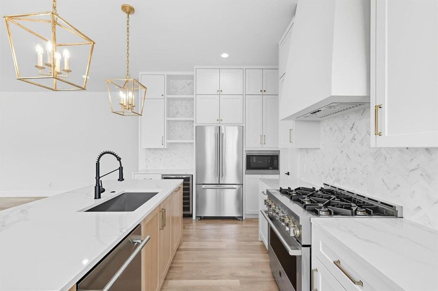 Kitchen with white cabinetry, light brown cabinetry, appliances with stainless steel finishes, light wood-type flooring, and recessed lighting Kitchen with white cabinetry, light brown cabinetry, appliances with stainless steel finishes, light wood-type flooring, and recessed lighting